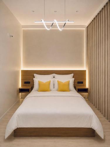 a bedroom with a large white bed with yellow pillows at Kigelia Hotel in Tumbes