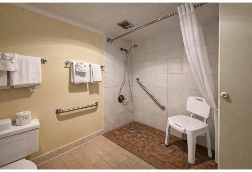 a bathroom with a shower with a toilet and a stool at Studio 6 Suites Rawlins WY in Rawlins