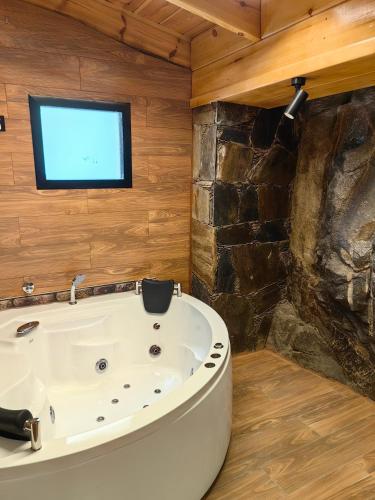 a bathroom with a tub and a tv on the wall at اكواخ لاكجري ابها in Abha