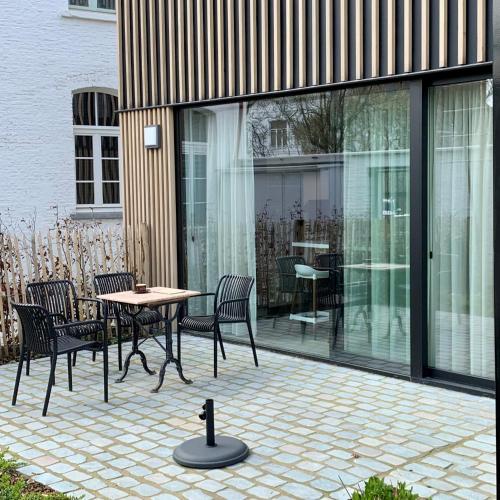 a patio with a table and chairs and glass doors at PATERSHOF vakantieverblijf in Diest
