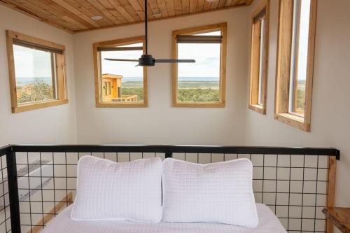 a bedroom with windows and a bed with white pillows at Tiny Cabin #3 at The Cedars in Kanab