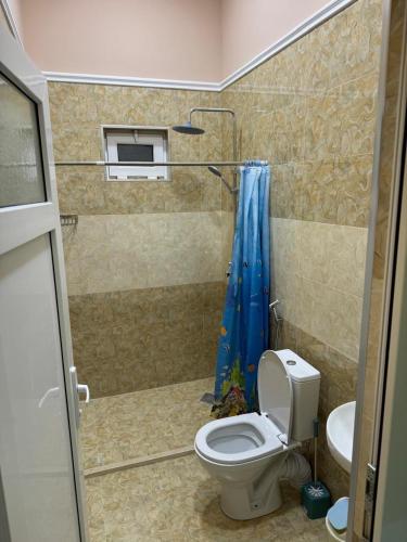a bathroom with a toilet and a blue shower curtain at Eco Otel in Quba