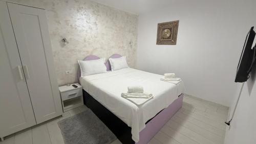 a small bedroom with a white bed with towels on it at Sab Luxury Apartments in Saturn