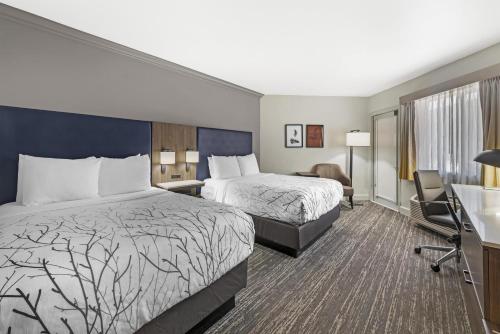 a hotel room with two beds and a desk at Best Western Denver East in Denver