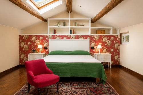 a bedroom with a bed and a red chair at Villa Al Sicomoro in Grezzana