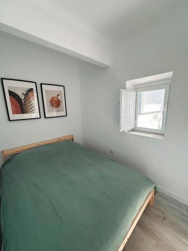a bedroom with a green bed and a window at Casa Da Aldeia in Alcácer do Sal