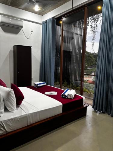 a bedroom with a large bed and a large window at Paris Garden Resort in Trincomalee