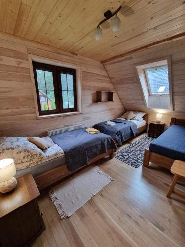 two beds in a room with wooden walls at Gajówka nad Serwami in Mołowiste