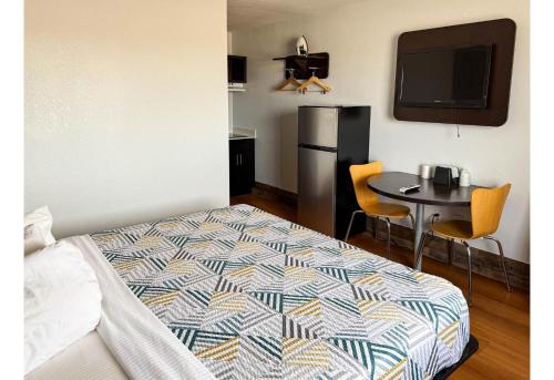 a bedroom with a bed and a table and a refrigerator at Studio 6 Pecos Texas in Pecos