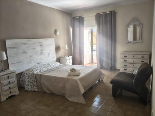 a bedroom with a bed and a chair and a dresser at La Maison dos Prazeres in Portimão