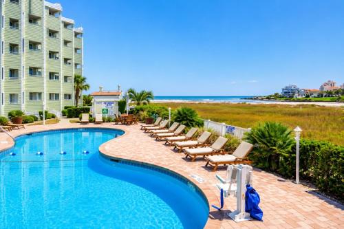 a swimming pool with lounge chairs and the beach at Sands Beach Club in Myrtle Beach