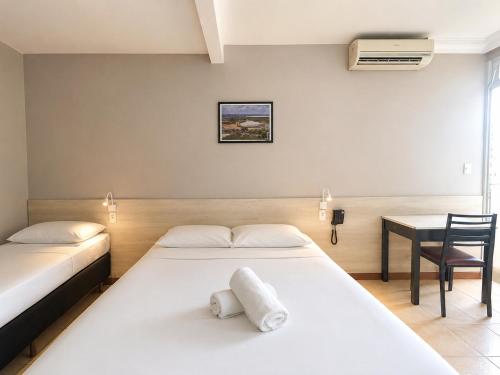 two beds in a room with a table and a desk at Hotel El Pilar by Bsb Inn in Brasília