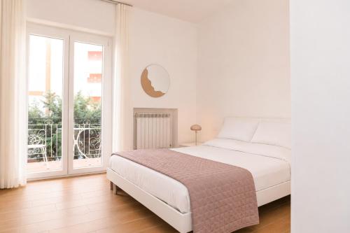 a white bedroom with a bed and a balcony at Nina Guest house in Gaeta