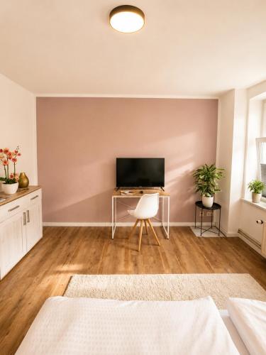 a living room with a television and a desk at Stilvolles Altbau-Apartment in zentraler Lage mit Workspace in Schwerin