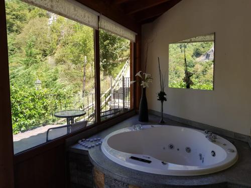 a large bath tub in a room with a large window at Hotel Puente Vidosa in Amieva