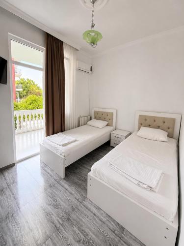 two beds in a white room with a window at Beliy Dom in Kvariati