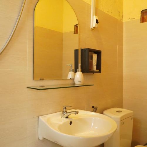 a bathroom with a sink and a mirror and a toilet at Nhà Để Chill Homestay in Da Lat
