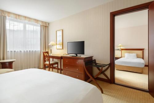 a hotel room with a bed and a desk with a television at Occidental Paris Levallois in Levallois-Perret