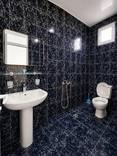 a black tiled bathroom with a sink and a toilet at Beliy Dom in Kvariati