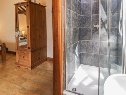 a shower with a glass door next to a mirror at Stabal-y-Gwedd in Llanddulas
