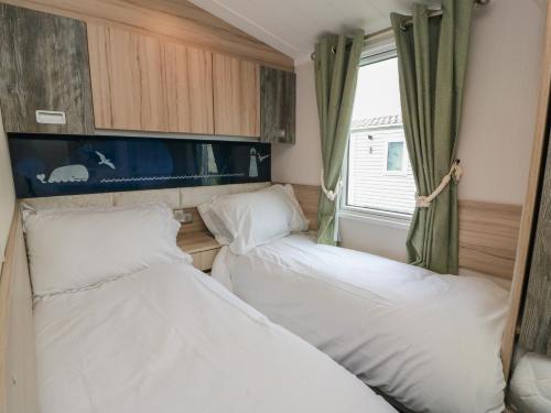 two beds in a small room with a window at Craig Tara Holiday Park 101 Bay View in Ayr