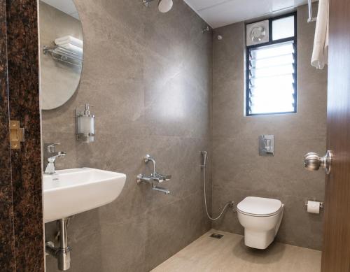 a bathroom with a sink and a toilet and a mirror at Hotel Pune Grand in Pune