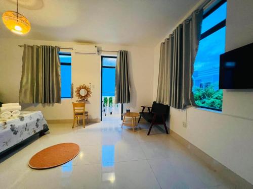 a living room with large windows and a room with a couch at KyNa House in Rạch Giá