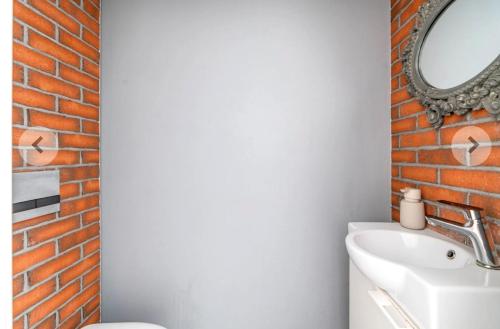 a bathroom with a brick wall and a mirror at Domino in Dąbrówka