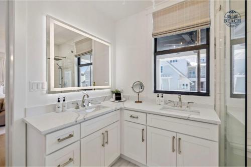 a white bathroom with two sinks and a window at Beach,Please in Rosemary Beach