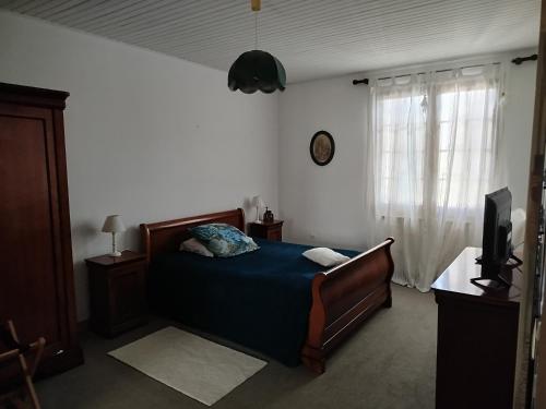 a bedroom with a bed and a tv and a window at LE LOGIS DE L'ETORE in Saint-Jean-dʼAngély