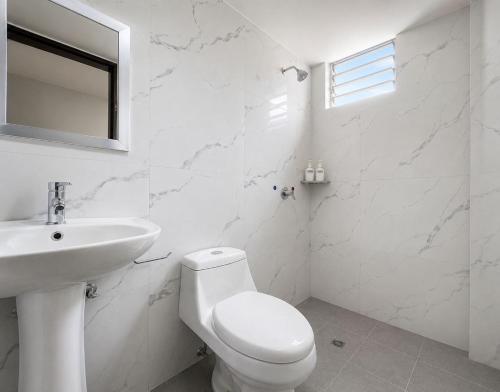 a white bathroom with a toilet and a sink at Villa Aurora 3 Bedroom 2 Baths in Baños