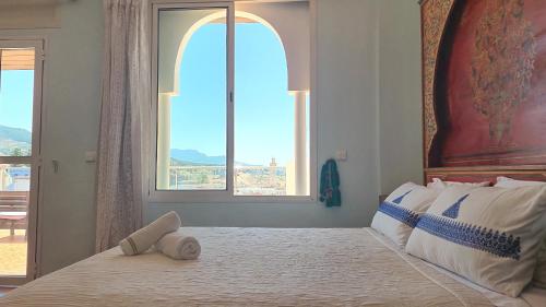 a bedroom with a large bed with a large window at Indigo House in Chefchaouen