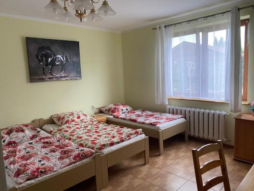 a room with two beds and a chair and a window at Rozalia in Stary Borek