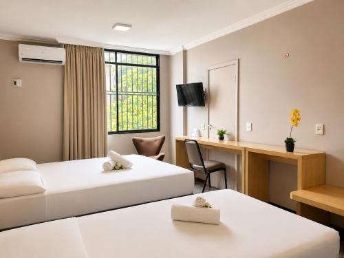 a hotel room with two beds and a desk at Hotel Diplomat by Bsb Inn in Brasília