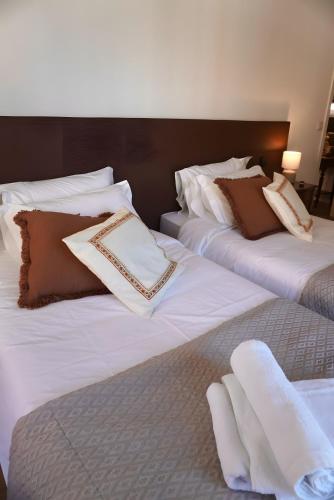 two beds with white sheets and brown pillows at Casas de São Roque in Vila do Conde