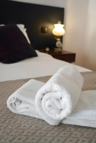 a stack of white towels on a bed at Casas de São Roque in Vila do Conde