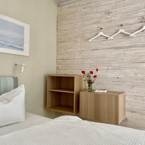 a bedroom with a wooden wall with a vase of red roses at Ferienwohnung EINS Hof Himmelgrün in Saal
