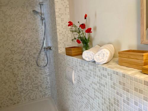 a bathroom with a shower with towels and a vase of flowers at Ferienwohnung EINS Hof Himmelgrün in Saal