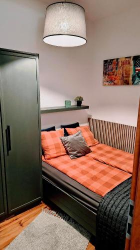 a bedroom with a bed with an orange comforter at Chrobry Square - Art Apartament in Gorzów Wielkopolski