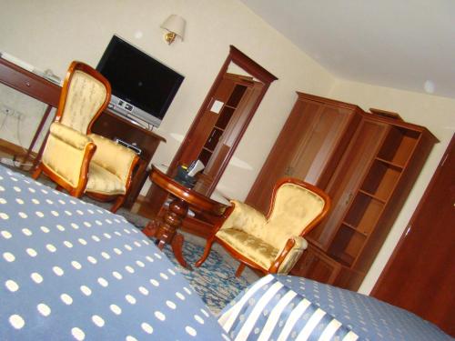 a room with two chairs and a table and a television at Hotel Vila Ariston in Osijek