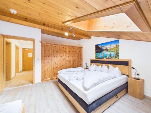 a bedroom with a large bed and a wooden wall at LUMA Stubai Aparthotel - Neueröffnung inklusive STUBAI SUPER CARD in Neustift im Stubaital