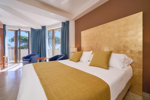 a bedroom with a large bed with yellow pillows at Hotel Terme Marine Leopoldo II TERME & SPA in Marina di Grosseto