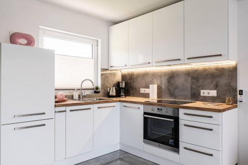 a white kitchen with white cabinets and a window at Domki Ostoja - nad Bałtykiem - cisza i piękno natury in Zastań