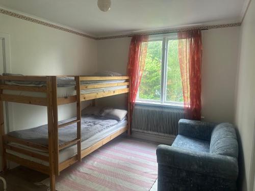 a bedroom with bunk beds and a couch and a window at Retro hus in Kosta