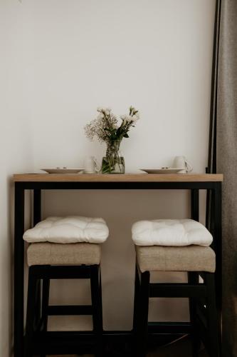 a table with two stools and a vase of flowers at Green Valley Accommodation in Lipovica