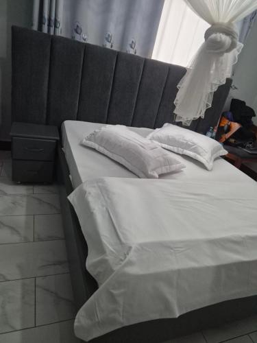 a bed with a black headboard and white pillows at Pearl Stay in Entebbe