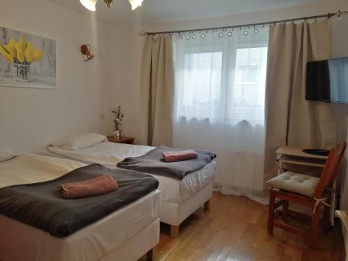 two beds in a room with a window and a chair at Sky&Lake Apartments Gdańsk in Gdańsk