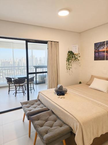 a bedroom with a large bed and a balcony at Studio Pôr do Sol - Garagem - Piscina - Anhembi in São Paulo