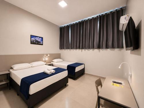 a hotel room with two beds and a desk and a tv at Vértice Hotel in Brasília