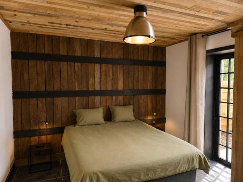 a bedroom with a bed with a wooden wall at VinOli Holiday Home in Alveringem